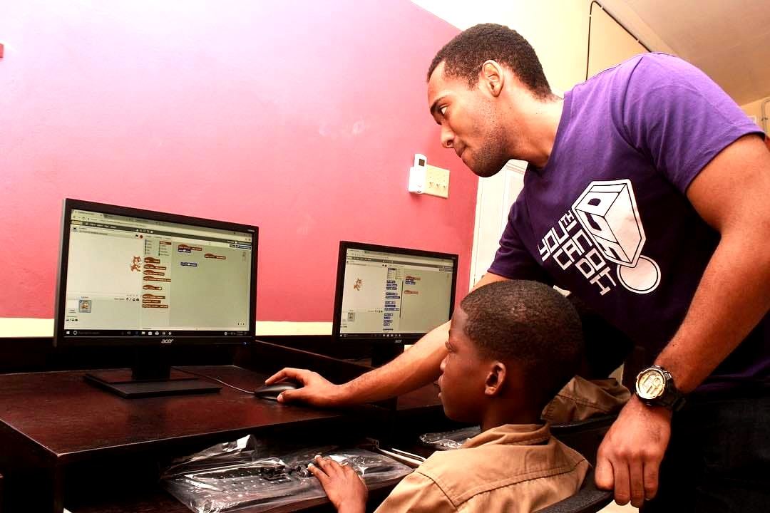 A YCDI change agent coaching a younger student at a computer